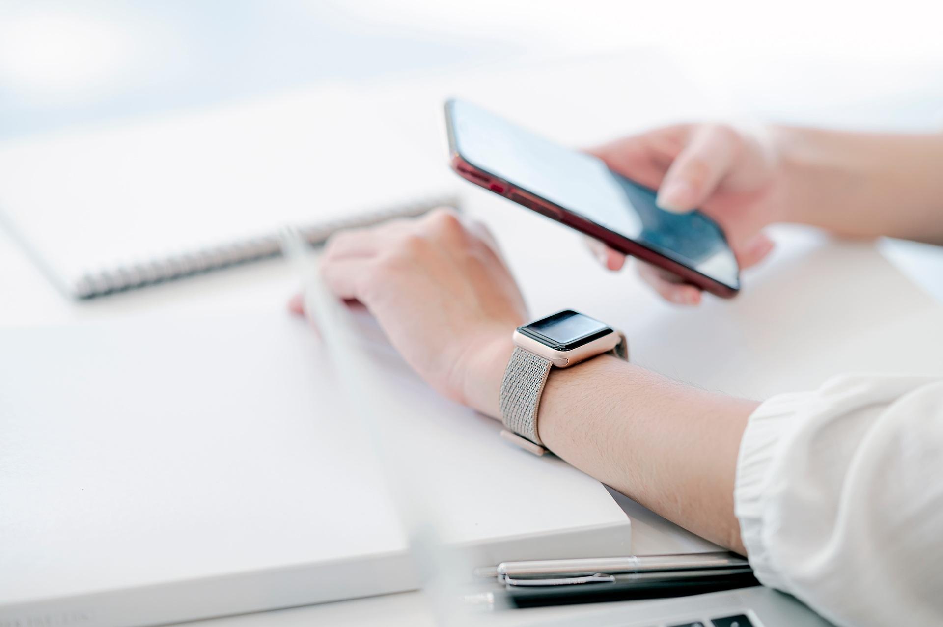 Person nutzt Smartphone und Smartwatch am Schreibtisch | Elf Bar Vape